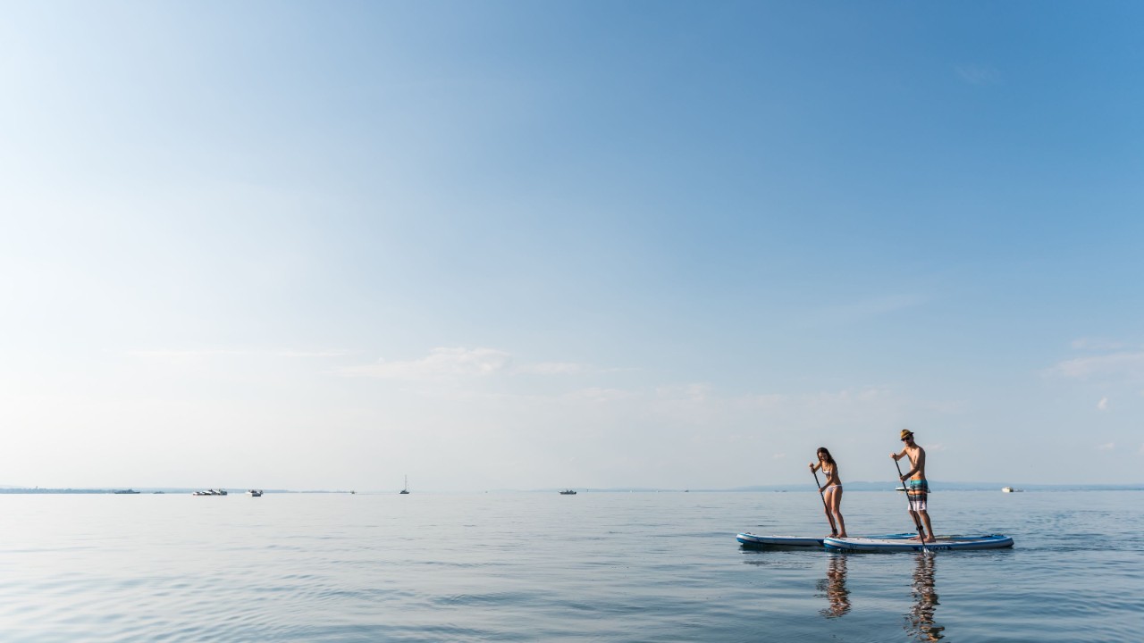 Foto di una tavola da SUP con due persone sul lago di Costanza.