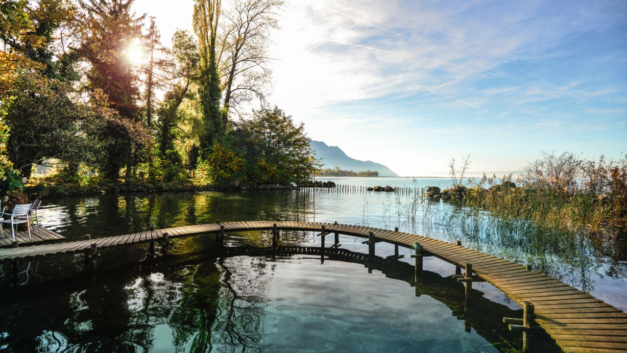 A wooden footbridge runs in a semi-circle along the shore of the lake.