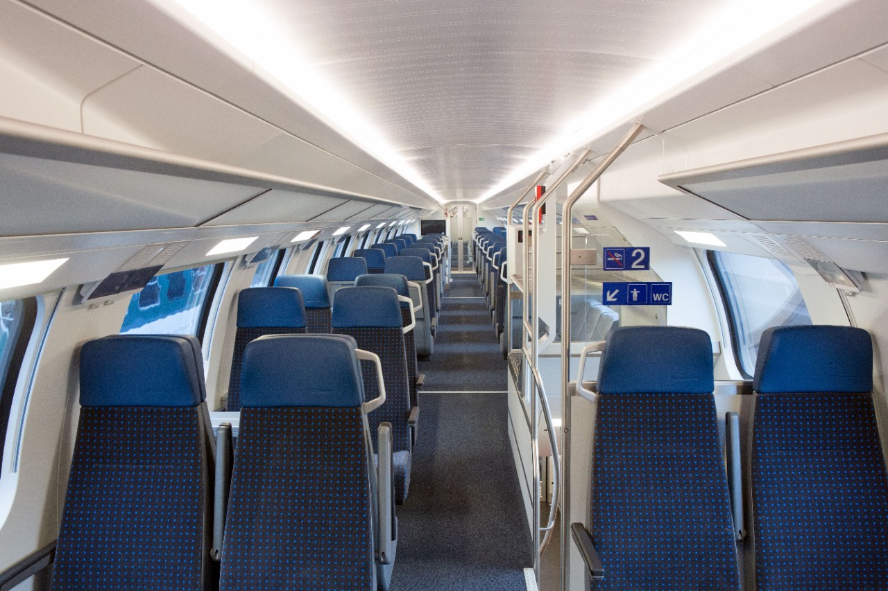 Allestimento interno di 2ª classe – Da entrambi i lati del corridoio si trovano compartimenti da quattro posti. I sedili sono di colore blu scuro. Sulla destra, tra i compartimenti si scorge una scala che conduce al piano inferiore. 